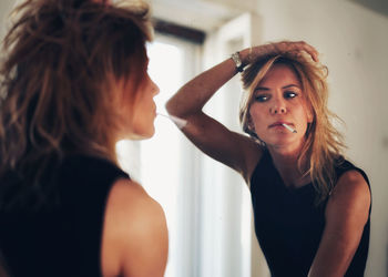 Portrait of beautiful young woman standing in mirror