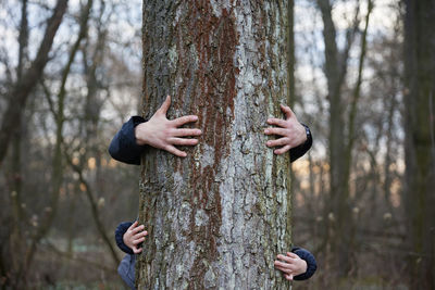 Dad and daughter hugging a tree in the woods.