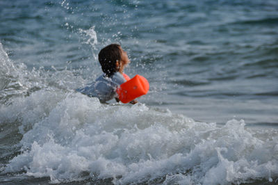 Playful girl with bucket playing on shore at beach