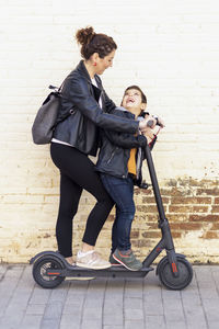 Mother and son riding on electric scooter in city