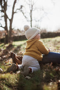 Mother and daughter wearing warm clothing while sitting on land