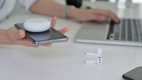 Midsection of person using mobile phone on table
