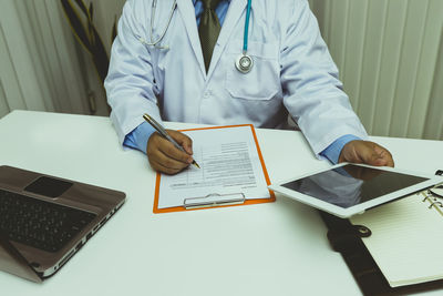 Midsection of doctor working on table