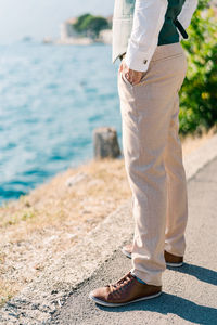 Low section of man walking on beach