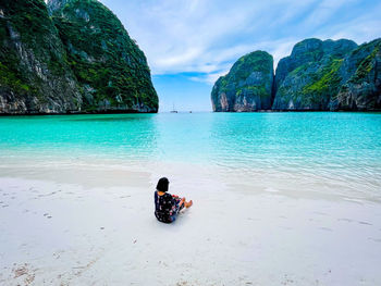 Rear view of woman swimming in sea against mountain