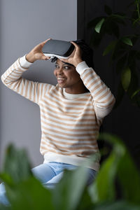 Curious joyful black woman feeling excited about vr helmet while spending free time at home