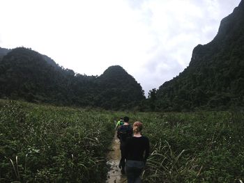 Rear view of man photographing on mountain against sky