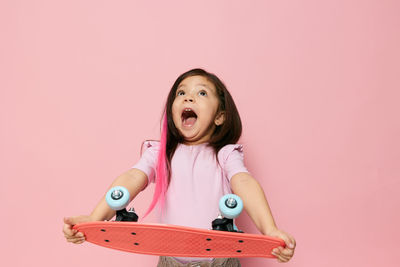 Portrait of smiling young woman against pink background