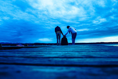 Rear view people on pier against sky