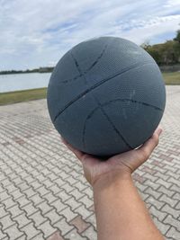 Close-up of hand holding water against sky