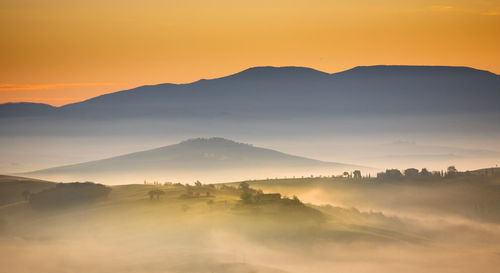 Scenic view of silhouette mountains against orange sky