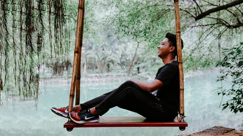 Side view of young man sitting on seat