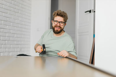 Portrait of young man using mobile phone while sitting on table