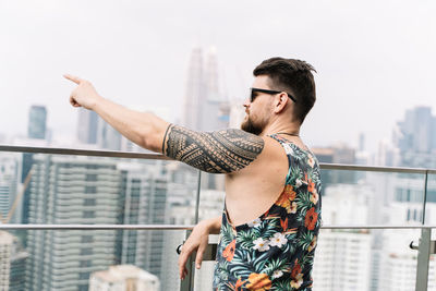 Full length of man standing by building in city against sky