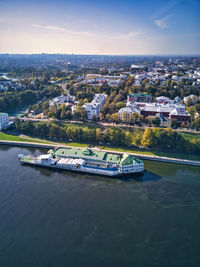 Aerial view of townscape by river against sky in city