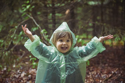 Charming child in a raincoat in the evening forest in denmark