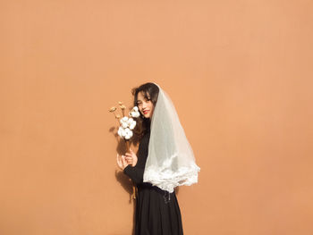 Portrait of bride standing against orange background