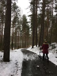 Rear view of girls walking on snow covered trees