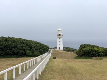Lighthouse amidst trees and buildings against sky