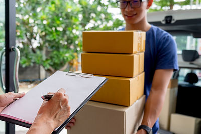 Cropped hands signing document while receiving delivery at home