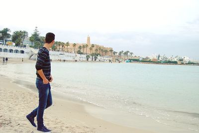 Full length of boy standing on beach against sky