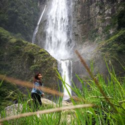 Side view of woman standing by waterfall