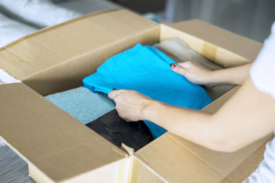 Midsection of woman packing clothes in cardboard box