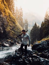 Man walking on rocks by stream at forest