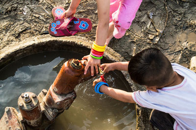 High angle view of boy and girl using water pump
