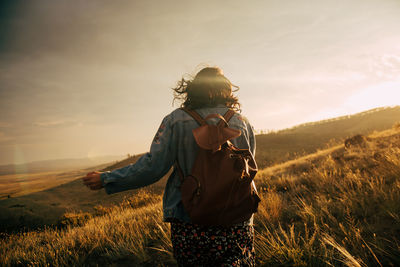 Woman standing on field against sky during sunset