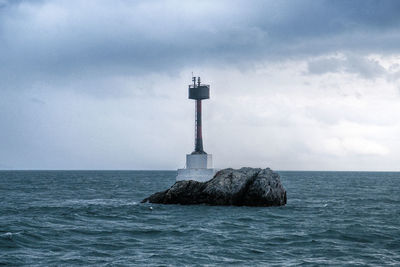 Lighthouse by sea against sky