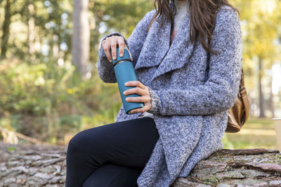 Midsection of woman sitting outdoors