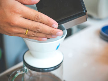 Cropped hands of woman preparing coffee on table in cafe