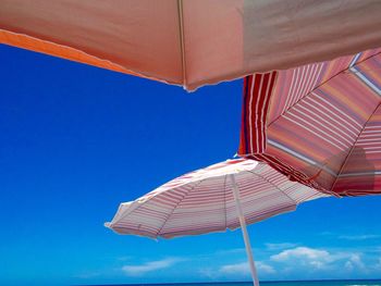 Low angle view of beach umbrellas against a blue sky