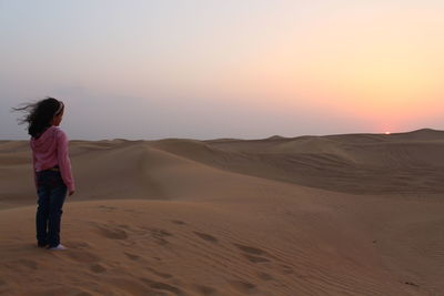 Full length of man on desert against sky during sunset