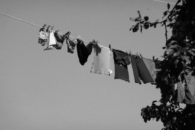 Low angle view of clothes hanging on rope against clear sky