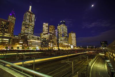 Illuminated modern buildings in city against sky at night