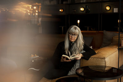 Mature woman in cafe reading book