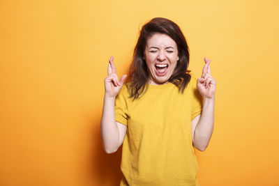 Portrait of young woman holding lollipop against yellow background