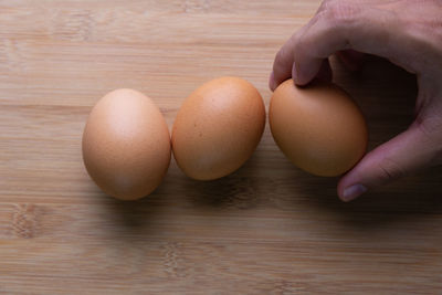 Close-up of hand holding eggs on table