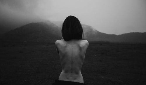 Rear view of woman standing on rock against sky