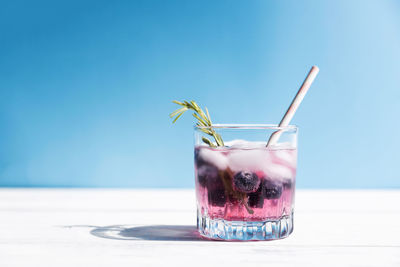 Chilled water, soda, cocktail with fresh blueberries and ice, garnished with a sprig of rosemary. 