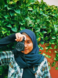 Portrait of young woman standing against plants