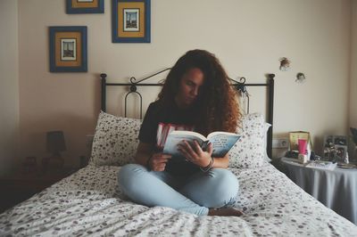 Young woman sitting on bed at home