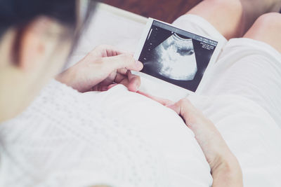 Midsection of woman using mobile phone on bed