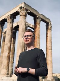 Low angle view of young man standing against old ruin