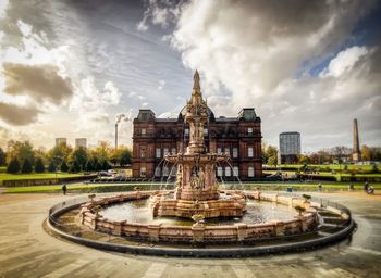 Fountain in city against sky