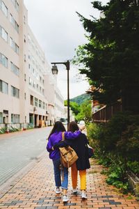 Rear view of female friends walking on sidewalk