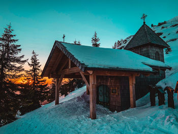 Built structure on snow covered building against blue sky