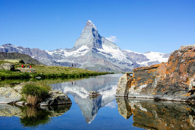 Scenic view of lake and mountains against blue sky